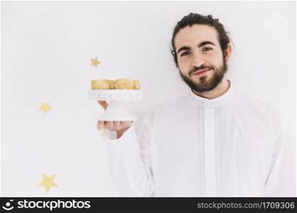 eid al fitr concept with man presenting arab pastry