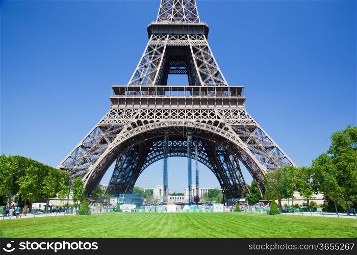 Eiffel Tower lower part seen from Champ de Mars at a sunny summer day, Paris, France
