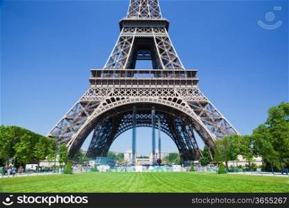 Eiffel Tower lower part seen from Champ de Mars at a sunny summer day, Paris, France