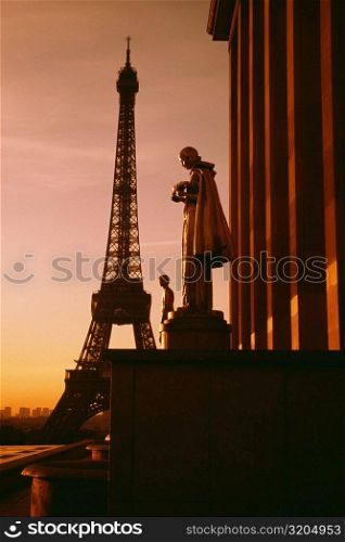 Eiffel Tower seen at the back of a palace statue at sunset, Paris, France