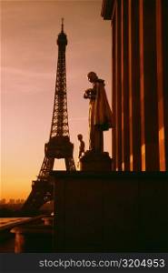 Eiffel Tower seen at the back of a palace statue at sunset, Paris, France