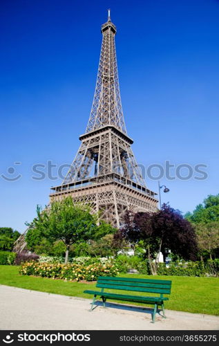 Eiffel Tower surrounded by the park with a bench, trees and flowers, Paris, France