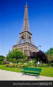 Eiffel Tower surrounded by the park with a bench, trees and flowers, Paris, France