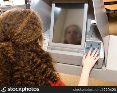 Eighteen year old girl voting for the first time on a touch screen machine.