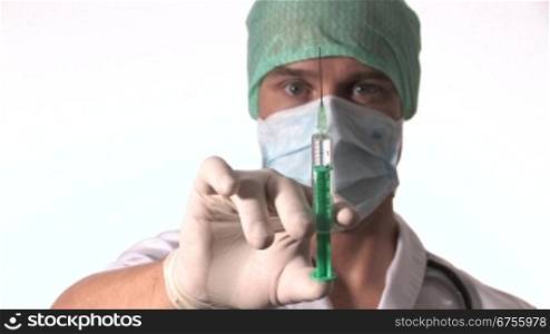 Ein Arzt hebt seine Hand und hSlt eine aufgezogene Injektion in die Kamera.