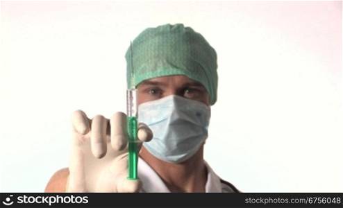 Ein Arzt hSlt eine aufgezogene Injektion in der Hand und senkt den Arm. Gleichzeitig fShrt die Kamera auf sein Gesicht zu.