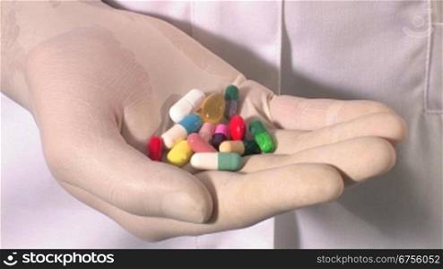 Ein Arzt oder eine Krankeschwester hSlt mehrere Pillen in der Hand, schliesst die Hand kurz und macht sie wieder auf