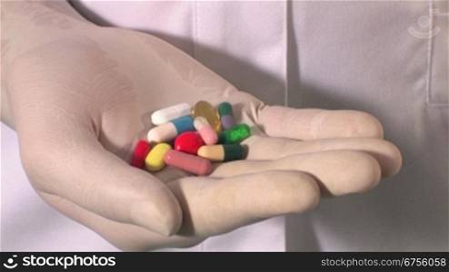 Ein Arzt oder eine Krankeschwester hSlt mehrere Pillen in der Hand und bernhrt diese mit dem Zeigefinger der anderen Hand