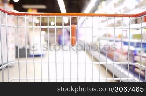 ein Einkaufswagen bewegt sich langsam durch einen Supermarkt
