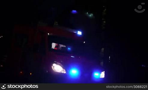Ein Einsatzwagen, Krankenwagen bzw. eine Ambulanz mit aktivierter Alarmleuchte nachts, a german ambulance car with flashing beacon is shown, emergency