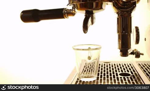 ein Espresso wird wird der Maschine zubereitet und lauft in ein durchsichtiges Glas an espresso machine is started and espresso runs into a transparent cup