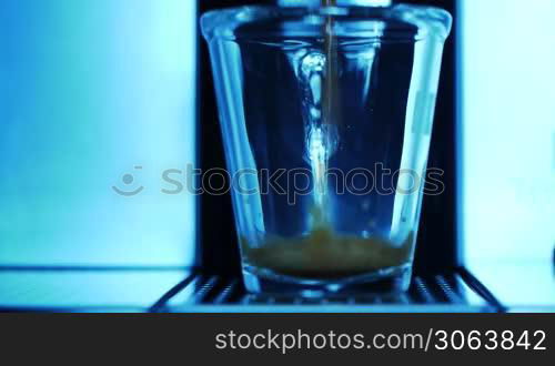 ein Espresso wird wird der Maschine zubereitet und lauft in ein durchsichtiges Glas an espresso machine is started and espresso runs into a transparent cup