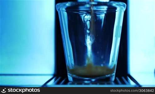 ein Espresso wird wird der Maschine zubereitet und lauft in ein durchsichtiges Glas an espresso machine is started and espresso runs into a transparent cup