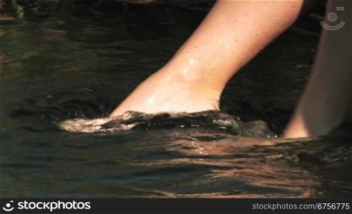 Ein Frau taucht Ihre Fnsse ins kalte Wasser