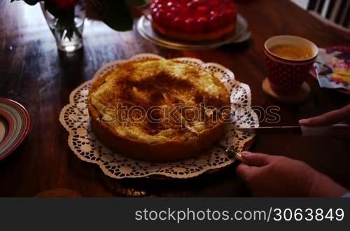 Ein Kuchen wird angeschnitten und ein Stuck auf einem Teller per Tortenheber serviert.