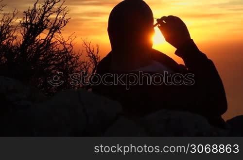 ein Mann beobachtet ein glei?end gelben Sonnenuntergang, Blickrichtung ist in die Sonne, so dass der Mann nur eine Silhouette bildet