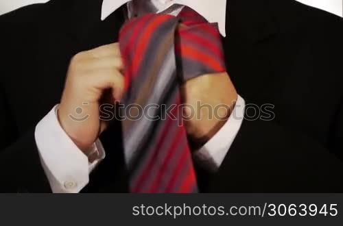 ein Mann bindet sich seinen Schlips um und macht einen Knoten