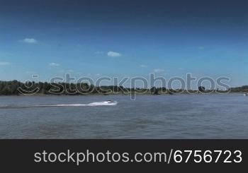 Ein Sportboot fShrt auf dem Rhein bei Tag mit dem Ufer als Hintergrund