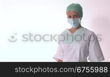 Eine Arzthelferin nimmt ihren Mundschutz weg und verschrSnkt die Arme
