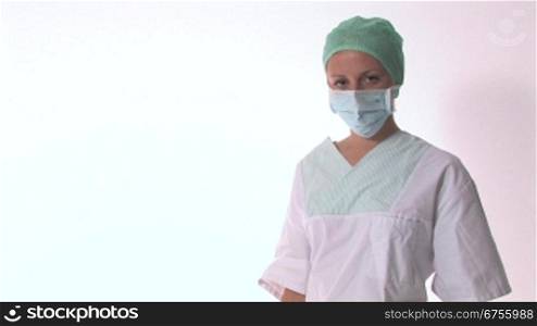 Eine Arzthelferin nimmt ihren Mundschutz weg und verschrSnkt die Arme