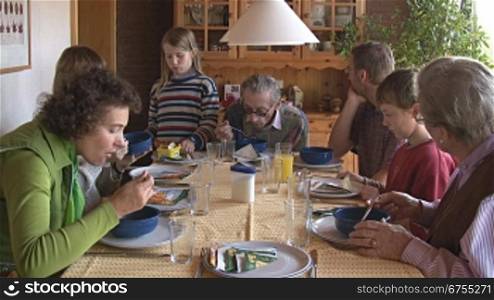 Eine Gro?familie sitzt beim gemeinsamem Essen am Esstisch; Vater, Mutter, Kinder und Gro?eltern.
