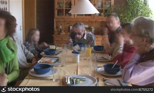 Eine Gro?familie sitzt beim gemeinsamem Essen am Esstisch; Vater, Mutter, Kinder und Gro?eltern.