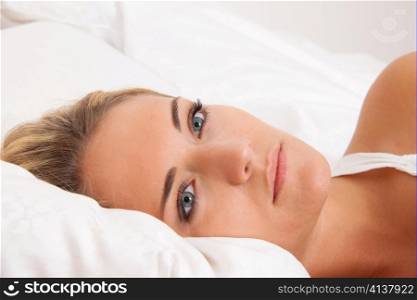 Eine junge Frau liegt wach im Bett. Schlaflos und nachdenklich.