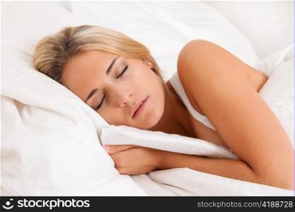 Eine junge hubsche Frau schlaft im Bett und erholt sich.