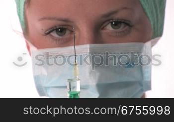Eine Krankenschwester hat eine Spritze vorbereitete und hSlt diese vors Gesicht