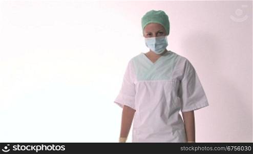 Eine Krankenschwester nimmt den Mundschutz runter, verschrSnkt die Arme und lacheld anschlie?end