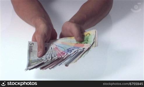 Eine Mann hSlt viele Euro Geldscheine in den HSnden und fSchert die Scheine auf.