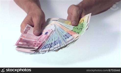 Eine Mann hSlt viele Euro Geldscheine in den HSnden, zShlt sie und fSchert die Scheine auf.