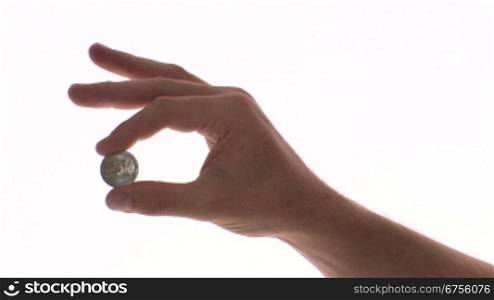 Eine Person hSlt ein 2-Euro Stnck zwischen Daumen und Zeigefinger und spielt damit