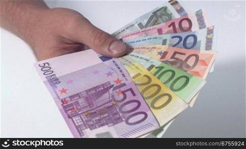 Eine Person hSlt mehrere Euro Geldscheine in der Hand