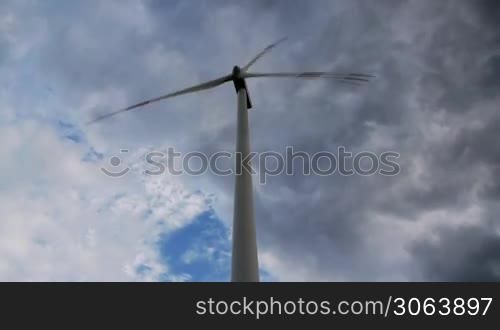 Eine Windanlage ist von vorne und aus extremer Perspektive, starke Untersicht, zu sehen, im Hintergrund ein eindrucksvoller Himmel