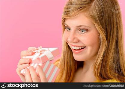 Elated girl opening gift isolated on pink background