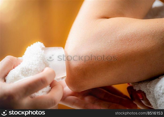 Elbow cryotherapy ice massage. Hands of a therapist placing ice directly onto a painful shoulder to relieve pain, reduce inflammation and swelling and promote healing.. Elbow Cryotherapy Ice Massage.