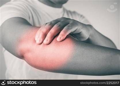 Elbow injury from tennis and golf. The man uses fingers to massage his arm. Pain symptom area is shown with red color. Healthcare knowledge. Medium close up shot with copy space. Black and white tone.