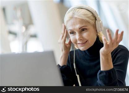 elder business woman having video call laptop with headphones