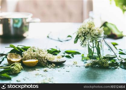 Elder flower syrup or jam preparation. Elderflowers and lemon on kitchen table at window. Home lifestyle. Healthy seasonal food eating and cooking