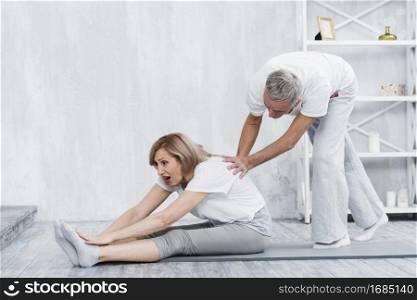 elder man helping his wife yoga position
