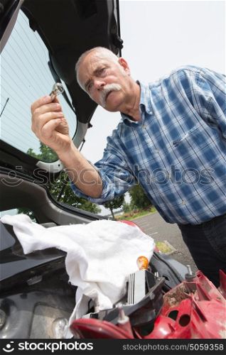 elder man servicing his car at home