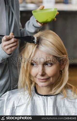 elder woman getting her hair dyed by hairdresser home