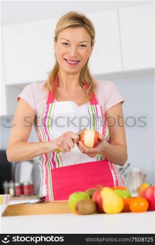 elder woman peeling apples in her kitchen