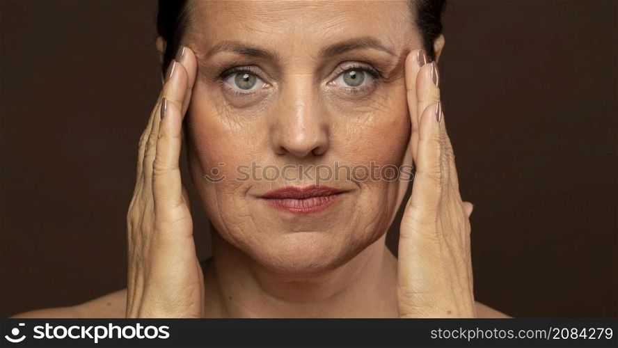 elder woman with make up posing while holding her temples