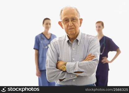 Elderly Caucasian male in foreground with two Caucasian females in the background.