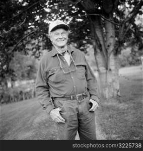 Elderly Caucasian Man Standing On A Country Road And Smiling