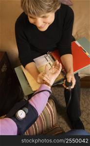 Elderly Caucasian woman at retirement community center receiving blood pressure test by nurse.