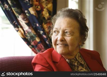 Elderly Caucasian woman by window at retirement community center.