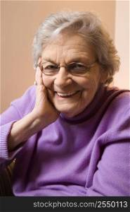Elderly Caucasian woman smiling with hand on face.